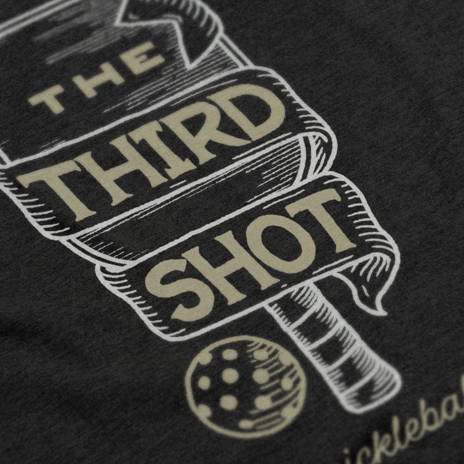 Close-up of Foundry pickleball shirt in black – wood cut old fashioned paddle graphic detail on back