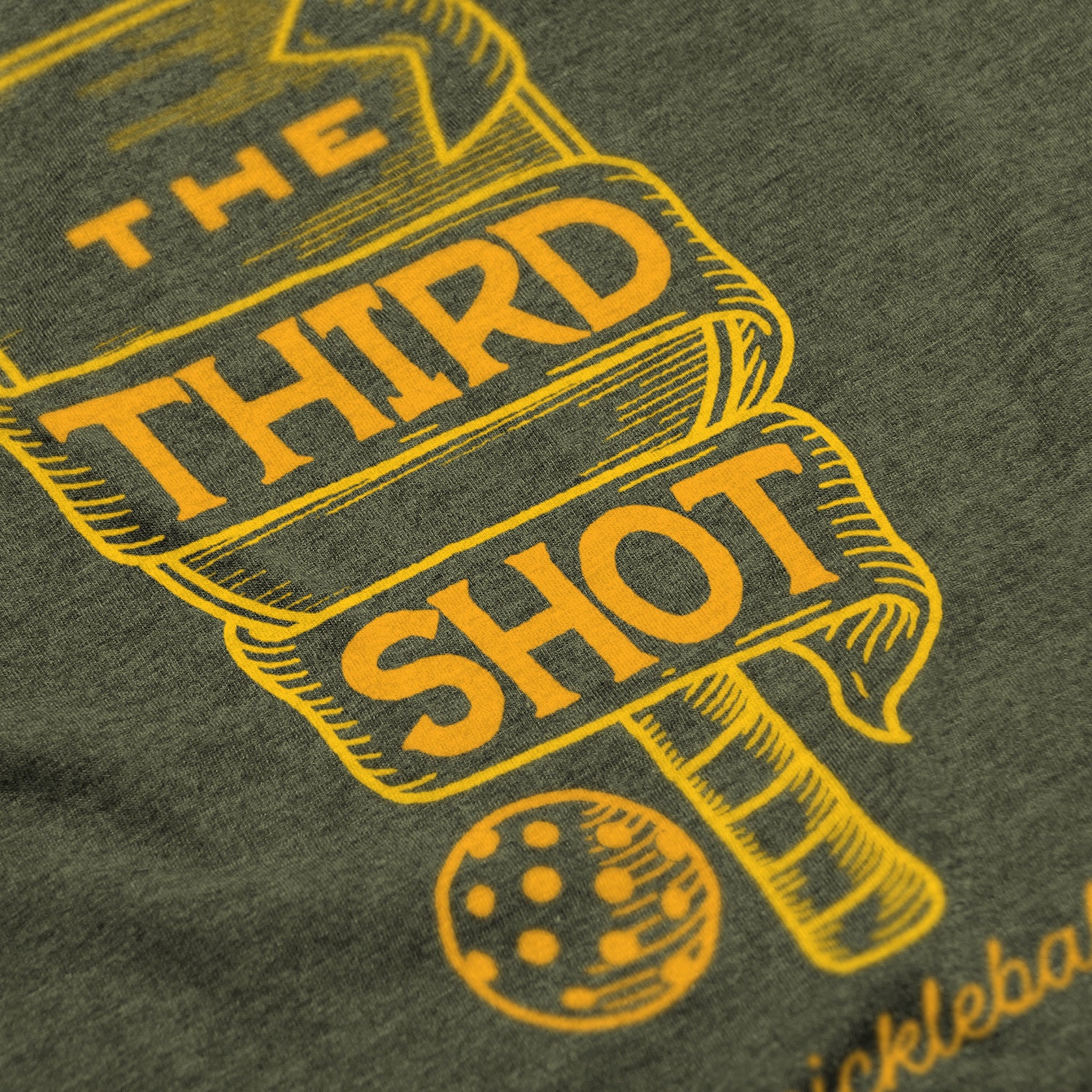 Close-up of Foundry pickleball shirt in military green – wood cut old fashioned paddle graphic detail on back
