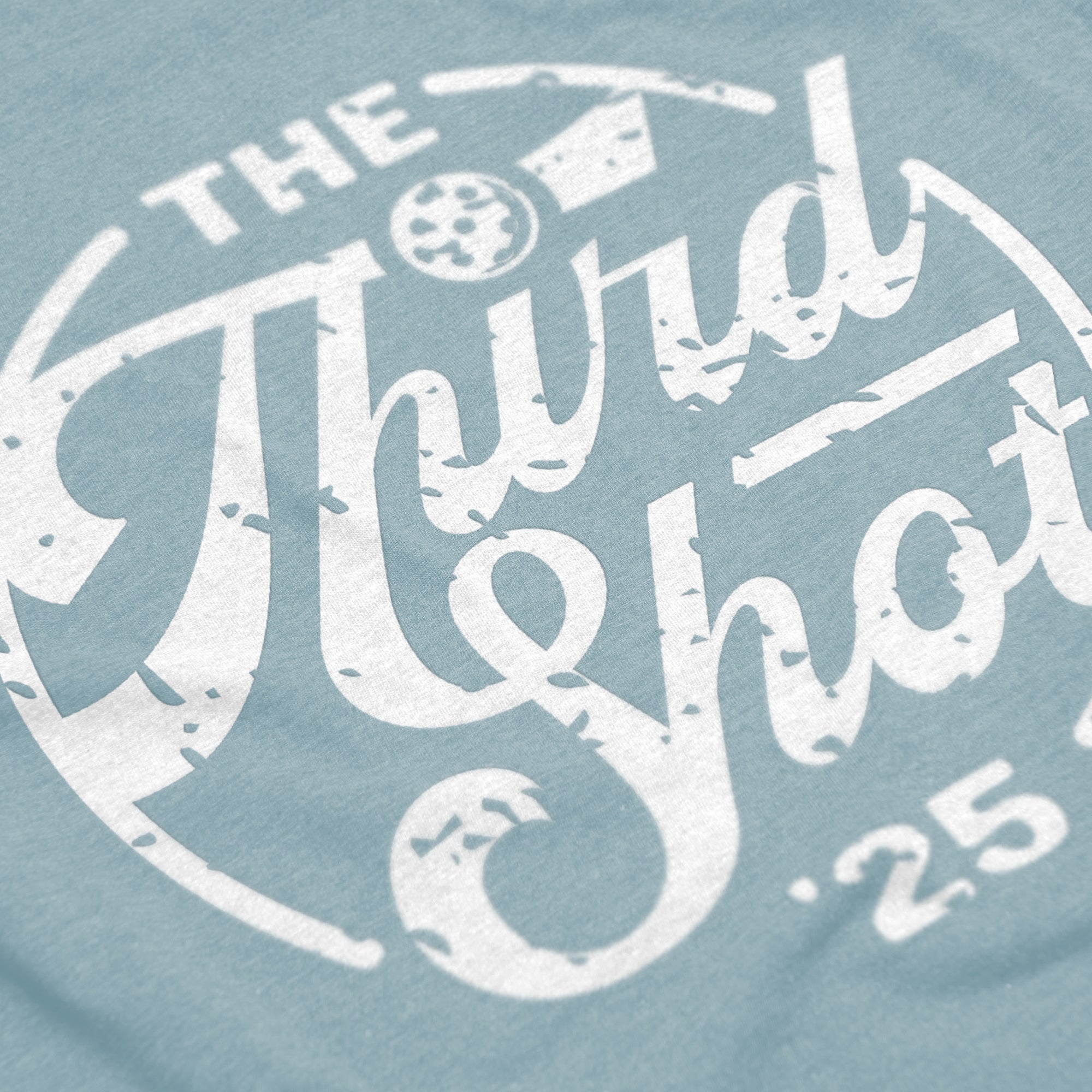 Close-up of Women’s Heritage pickleball shirt in blue – retro circular logo detail