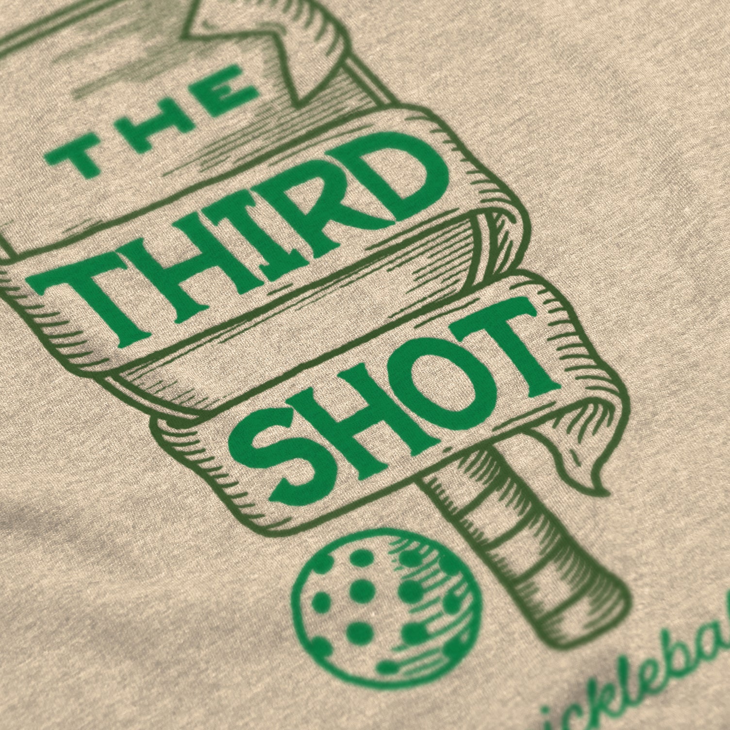 Close-up of Foundry pickleball shirt in creme – wood cut old fashioned paddle graphic detail on back